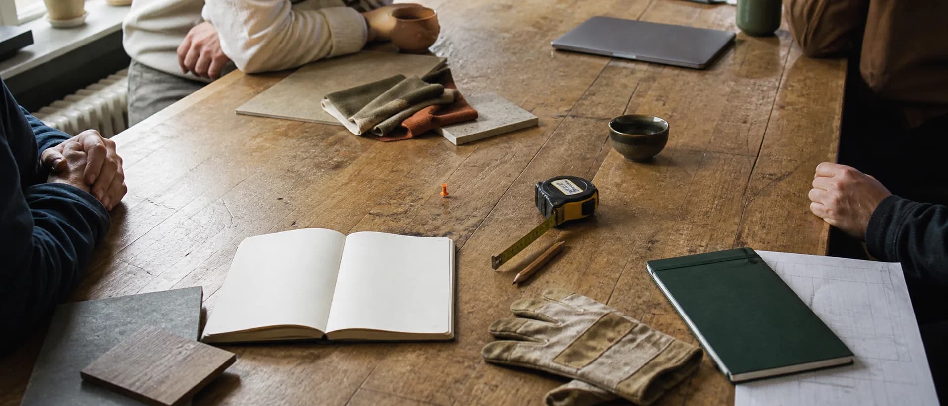Werktafel met notitieboek, werkhandschoenen, stalen en meetgereedschap van verschillende vakmensen